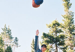 a man pointing up to food bags hanging from a line between two trees