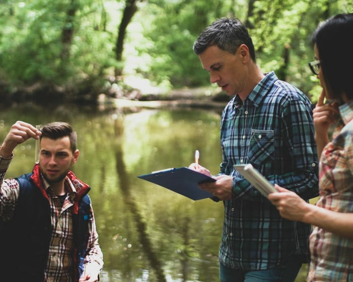 A group of people taking water samples from a pond