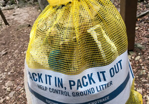 a mesh trash bag with the slogan "pack it in. pack it out."